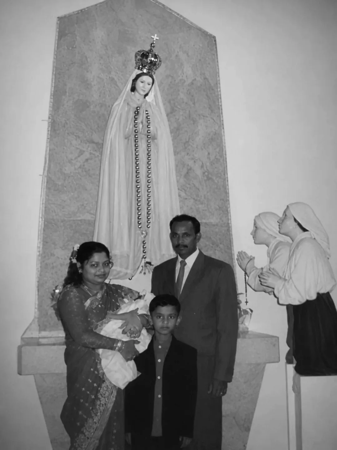 A family portrait beside a statue of the Virgin Mary